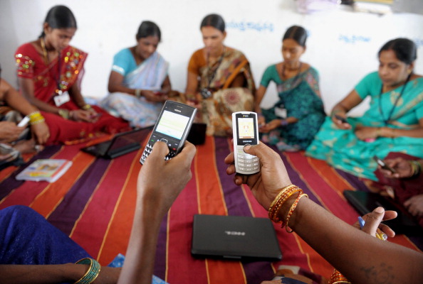 Indian villagers part of a Self Help Group organisation pose with mobile phones and laptops in Bibinagar village outskirts of Hyderabad