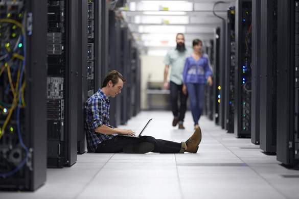 Man Sitting in Data Center with Notebook