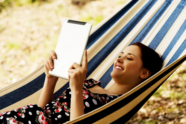 Woman Relaxing In Hammock With E-Book